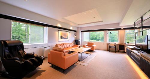 a living room with a couch and chairs and windows at Villa the Club Karuizawa in Naganohara