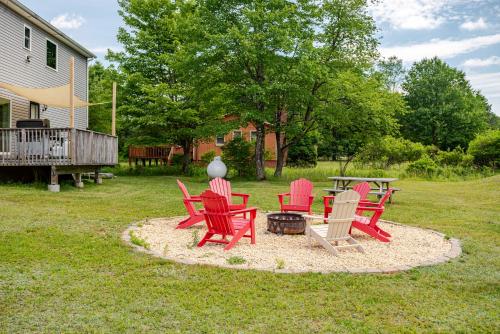 a group of red chairs and a table in a yard at Huge villa in the hearth of Poconos near all. in Long Pond