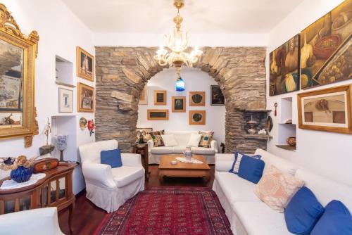 a living room with a white couch and a stone wall at Gladiolus House - Tinos in Tzádhos