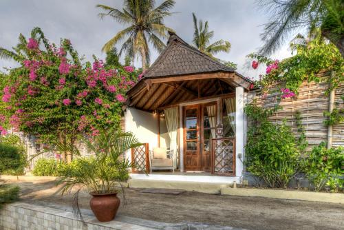 a small house with pink flowers in front of it at Les Villas Ottalia Gili Meno in Gili Meno