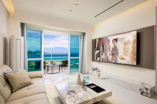 a living room with a white couch and a large window at Sanya Sun Seaview Apartment in Sanya