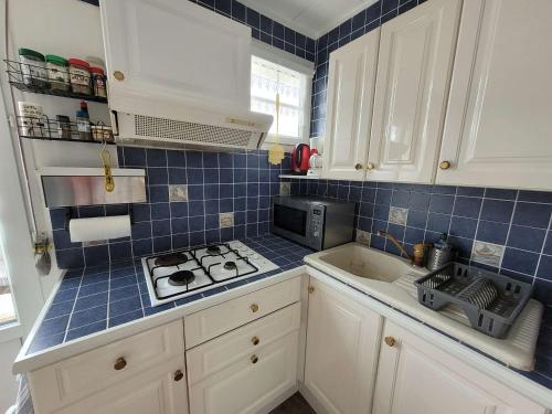 une cuisine avec des placards blancs et du carrelage bleu sur le mur. dans l'établissement Appartement cosy 4 pers avec balcons à 2 min de la plage - FR-1-672-36, à Merlimont