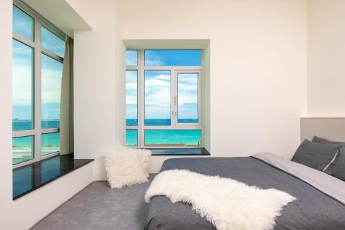 a bedroom with a bed with a view of the ocean at Sanya Sun Seaview Apartment in Sanya