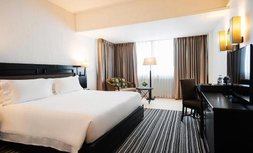 a hotel room with a large white bed and a desk at Centara Hotel Hat Yai in Hat Yai