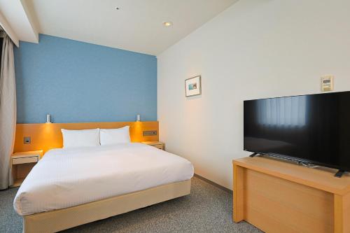 a bedroom with a bed and a flat screen tv at JR Kyushu Hotel Miyazaki in Miyazaki