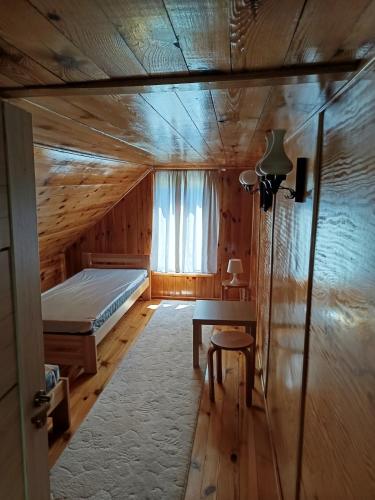 a bedroom with a bed and a table and a window at Domek nad Pisą in Kolno
