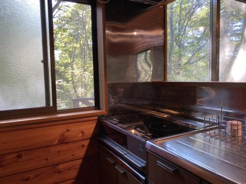 a kitchen with a stove and two windows at 花の街662#Private villa in Azumaiokozan