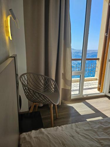 a bedroom with a chair in front of a window at Nisaki Hotel & Elite Suites in Ermoupoli