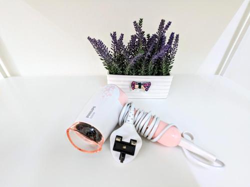 a white table with a vase with purple flowers and a whisk at Private Room with Bathroom in Kuala Lumpur