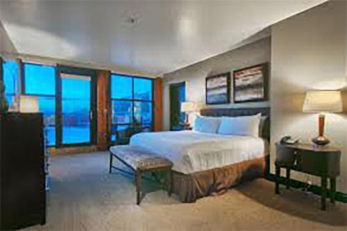 a bedroom with a large bed with a desk and windows at Main & SKY by EXMAR in Park City