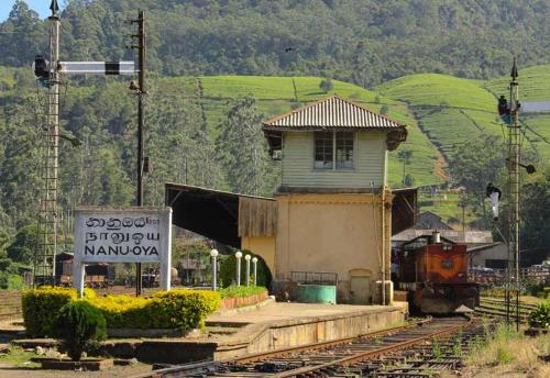 a train station with a building and a train on the tracks at Green Mount View Two Bed Room Apartment in Nuwara Eliya