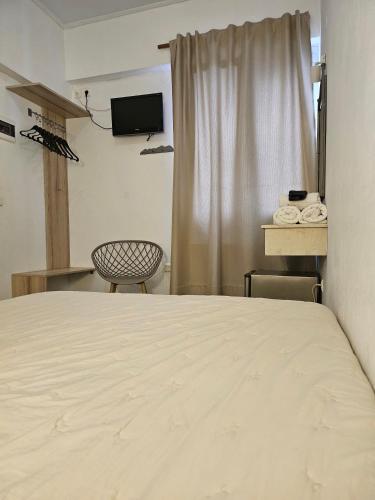 a room with a bed and a chair and a window at Nisaki Hotel & Elite Suites in Ermoupoli