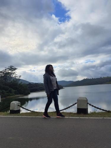 a woman walking on a road next to a lake at Green Mount View Two Bed Room Apartment in Nuwara Eliya