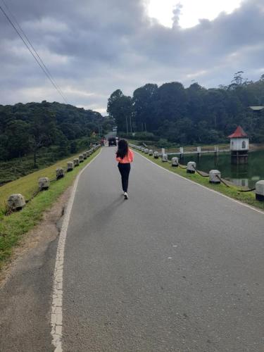 a woman walking down a road in the middle of the road at Green Mount View Two Bed Room Apartment in Nuwara Eliya