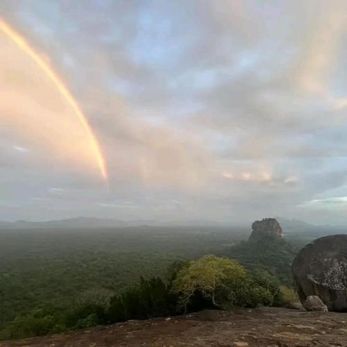 a rainbow in the sky over a mountain at Sigiri Birds Hostel in Sigiriya