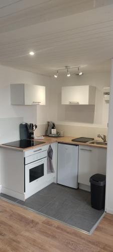 La cuisine est équipée de placards blancs et d'un four avec plaques de cuisson blanches. dans l'établissement Appartement à 300m de la plage avec parking privé, à Camiers