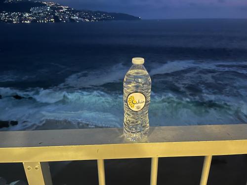 a bottle of water sitting on a railing near the ocean at Torres Gemelas Suite VIP Frontal 607 in Acapulco