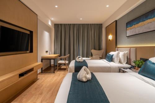 a hotel room with two beds and a flat screen tv at Copper Leaf Hotels, Tirunelveli in Tirunelveli