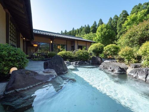 a river with rocks in front of a house at 天空の湯屋 山荘 華柚 in Oguni