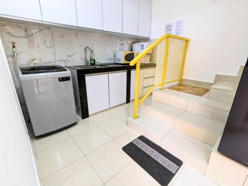a kitchen with white cabinets and a yellow staircase at Private Room with Bathroom in Kuala Lumpur