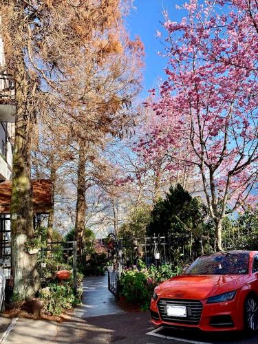 a red car parked in a driveway with flowering trees at The Cotswolds Villa in Renai