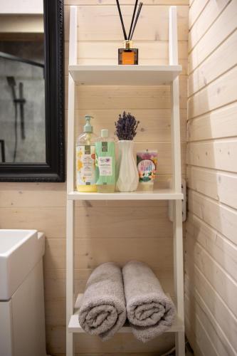 a bathroom with a sink and towels on a shelf at Mystica Forest in Braziūkai