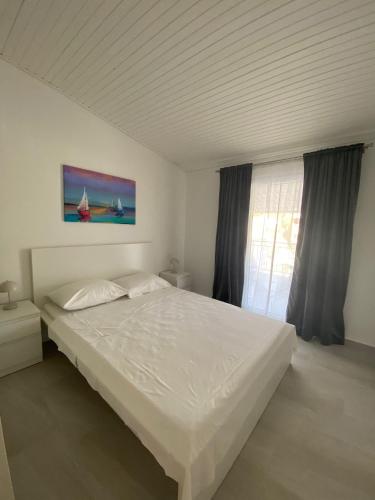 a white bed in a bedroom with a window at Apartmani Gršćica 2 in Blato