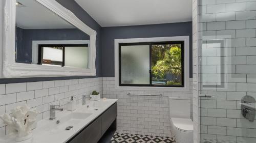 a bathroom with two sinks and a toilet and a window at Jewelers Retreat in Pearl Beach