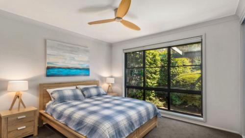 ein Schlafzimmer mit einem Bett und einem großen Fenster in der Unterkunft Opal Oasis in Pearl Beach