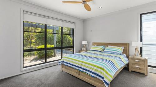 ein Schlafzimmer mit einem Bett und einem großen Fenster in der Unterkunft Opal Oasis in Pearl Beach