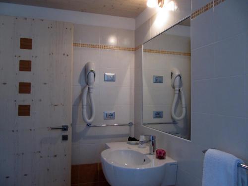 een witte badkamer met een wastafel en een spiegel bij Affittacamere Famiglia Ceschini in Tesero