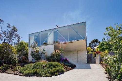 una casa con ventanas de cristal y plantas delante de ella en Architectural glass house with ocean views, en Taroona