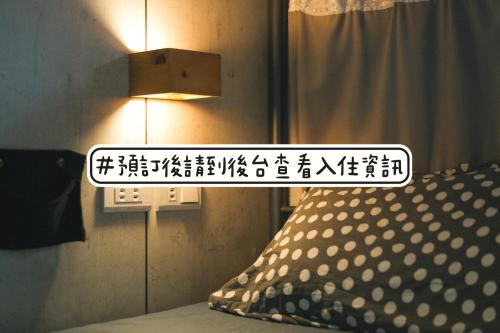 a sign in a room with a bed and a lamp at Loft18 Hostel in Tainan