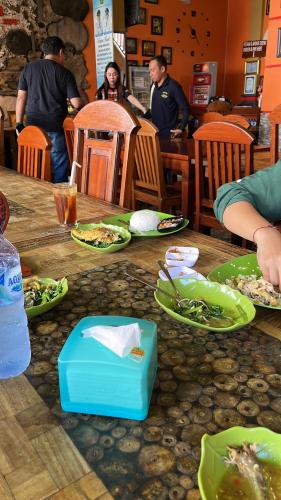 a wooden table with plates of food on it at Rega house in Meliling