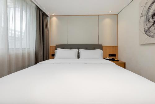 a bedroom with a large white bed and a window at Waito Hotel Yuexiu Park Guangzhou in Guangzhou