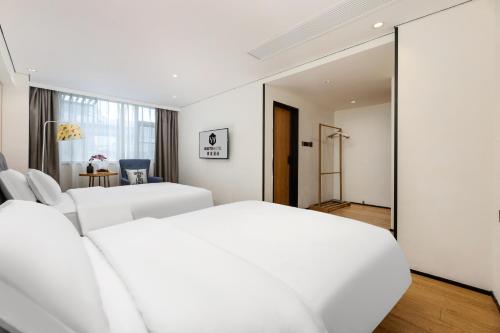 a white bedroom with two beds and a mirror at Waito Hotel Yuexiu Park Guangzhou in Guangzhou