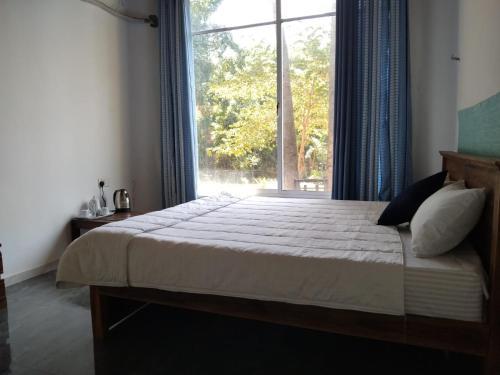 a bedroom with a bed and a large window at Esha Beach Resort Rooms in Trincomalee