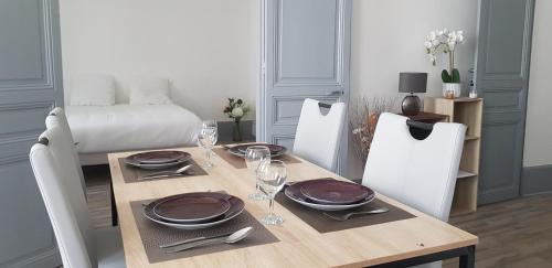 a dining room with a table with plates and wine glasses at Cosy 4 minutes à pieds du centre historique avec parking in Montluçon