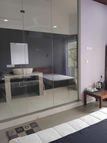 a bathroom with a glass wall with a bed in it at Esha Beach Resort Rooms in Trincomalee