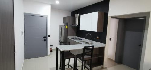 eine Küche mit Spüle und Theke mit Hockern in der Unterkunft Hermoso departamento para vacacionar in Mazatlán