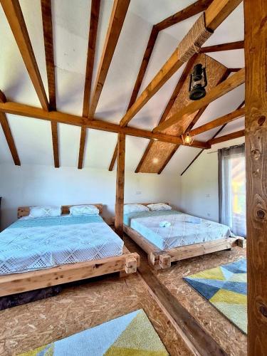 two beds in a room with wooden ceilings at GREEN MOON Breza in Breza