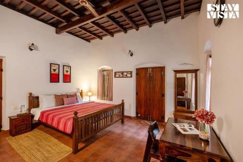 a bedroom with a large bed and a table at CVM House with Lawn at Thiruvalla by StayVista in Alleppey