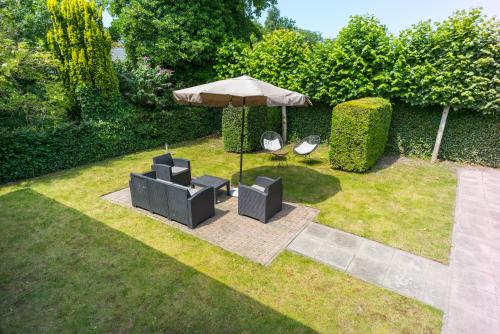 a garden with two chairs and an umbrella at Roggebroek 44 in Stavoren