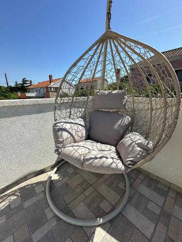 a hanging chair with pillows on a patio at ILOVIK FLOWER in Ilovik