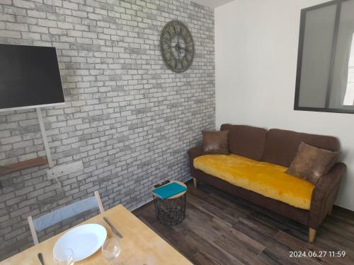 un salon avec un canapé et un mur de briques dans l'établissement Charmant et cosy 200m de port, à La Ciotat