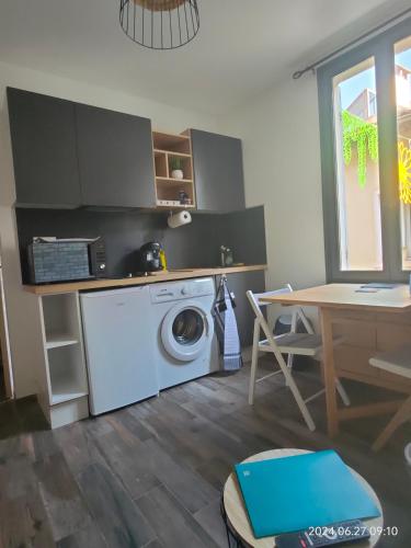 une cuisine avec une machine à laver et une table dans l'établissement Charmant et cosy 200m de port, à La Ciotat