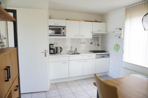 a kitchen with white cabinets and a table at Kustverhuur, Park Schoneveld stern 266 in Breskens