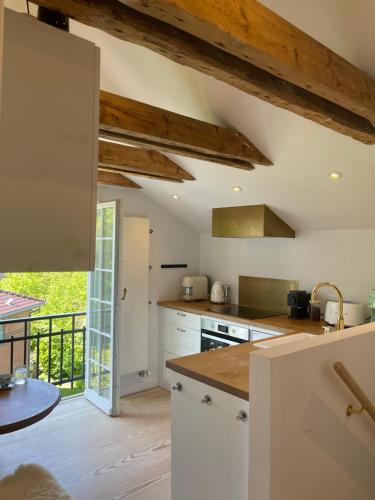 a kitchen with white cabinets and wooden ceilings at Eksklusiv taglejlighed med hav- og skovudsigt in Risskov