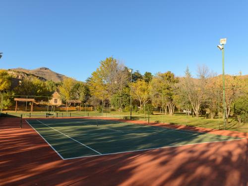 a tennis court with trees and mountains in the background at Kiara Lodge in Clarens