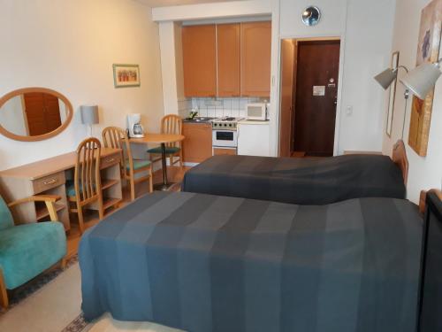 a room with two beds and a table and a kitchen at Ikaalisten kylpylä-hotelli in Ikaalinen